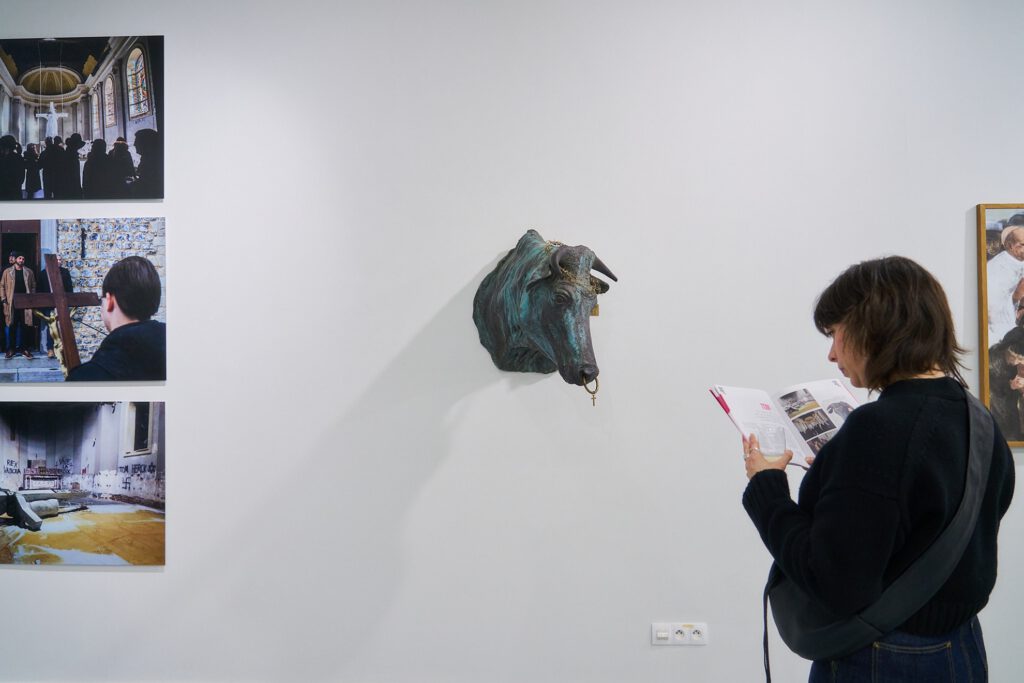 Femme lisant un livret devant une caricature religieuse.