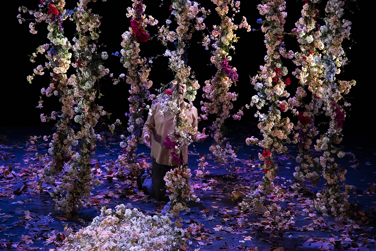 Des torsades de fleurs entourent Pippo Delbono, comme une forêt, ou une prison.