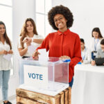 Young,Voter,Woman,Smiling,Happy,Putting,Vote,In,Ballot,Standing
