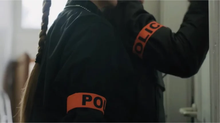 Visites domiciliaires : photographie de deux policiers le brassard enroulé autour du bras et l'un d'eux frappant à la porte d'un logement avant de procéder à une visite domiciliaire.